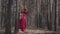 Skill young woman in red dress dancing in the forest landscape. Beautiful dancer showing classic ballet poses. Concept