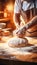 Skilled baker carefully kneading dough for baking bread in bakery with blurred background