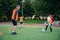 Skilled child player in football uniform working out the kicking ball together with his experienced coach on sport field