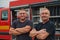 A skilled and dedicated professional firefighting team proudly poses in front of their state of the art firetruck