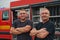 A skilled and dedicated professional firefighting team proudly poses in front of their state of the art firetruck