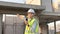 Skilled engineer inspects factory construction and uses a radio to chat with colleagues working on the field