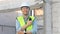 Skilled engineer inspects factory construction and uses a radio to chat with colleagues working on the field