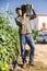 Skilled farmer carrying bucket of freshly picked tomatoes on his shoulder