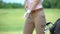 Skilled female golf player wearing white glove bag with iron clubs nearby, hobby