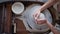 skilled female potter is working with pottery wheel in workshop, top view