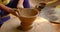 Skilled hands of potter shaping the clay on potter wheel and sculpting clay pot jar. Shilpagram, Rajasthan, India