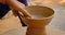 Skilled hands of potter shaping the clay on potter wheel and sculpting clay pot jar. Udaipur, Rajasthan, India