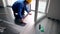 Skilled handyman guy with yellow hard hat installing laminate boards on floor