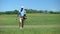 Skilled male golf trainer walking on course with clubs bag recreational activity