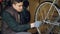 Skilled mechanic is rotating bicycle wheel checking mechanism and turning treadle while fixing bike. Professional cycle