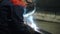 A skilled welder fuses metal with a welding torch with sparks