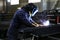 Skilled Welder in protection at Work with Sparks Flying in Industrial Workshop