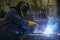 Skilled Welder in protection at Work with Sparks Flying in Industrial Workshop