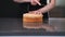 Skilled woman using string knife for separating cake layers in modern kitchen