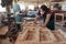 Skilled woodworker sanding furniture in his large workshop