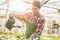 Skilled young man watering houseplants while working as florist