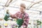 Skilled young man watering houseplants while working as florist