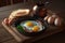 A skillet with eggs, mushrooms, bacon, and toast on a wooden table with eggs and bread on a plate next