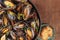 Skillet of marinara mussels on rustic background with bread and copy space