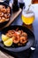Skillet roasted jumbo shrimp on a black plate. Beer pouring into a glass.
