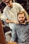 Skillful barber making haircut too bearded customer