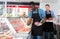 Skillful butcher with colleague working behind counter