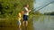 Skillful dad and little boy with fishing poles catching fish on lake