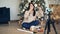 Skillful girl creative vlogger is recording video about gift boxes and present wrapping sitting near decorated Christmas