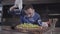 Skillful man in cook uniform preparing tasty dish wrapped in lavash. Chef in white rubber gloves pouring lettuce leaves