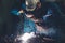 Skillful metal worker working with arc welding machine in factory