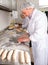 Skillful people working at bakery, preparing raw baguette dough for baking