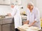 Skillful people working at bakery, preparing raw baguette dough for baking