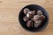 Skin-on boiled taro corm in a black crockery on a wooden table.