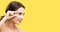 Skin care beauty. Ðappy smiling woman pointing, touching skin, applying cream. yellow background. copy space