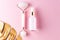 Skin care concept. Bottle of cometic product, serum or oil. Quartz roller for face massage. Cosmetics and tools on pink background