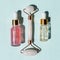 Skin care concept. Bottles of cometic product, serum or oil. Quartz roller for face massage. Cosmetics and tools on blue