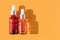 Skin-care cosmetic products with vitamin C and fruit essence. Dropper bottles with face beauty oil or over orange background