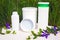Skin care cosmetics, beauty, white bottles on a background of green grass with branches of purple wildflowers close-up.