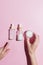 Skin care cosmetics set. Three steps foutine for healthy skin. Female hand choosing a jar of cream or bottle with essence. Pink