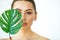 Skin Care. Green Leaf Shading a Half of Beautiful Woman Face. Be