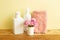 Skin care and spa concept. Bathroom bottles and towel with pink flowers on wooden shelf