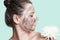 Skin care. Woman with black facial mask and white flower