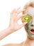 Skin care. Woman in clay mask with kiwi on face