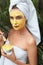 Skin Care. Woman With Yellow Clay Mask On Face. Female In Bath Towel With Brush For Applying Beauty Product.