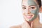 Skin Care. Young woman with cosmetic clay mask holding cucumber