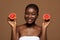 Skin Detox Concept. Cheerful Young Black Woman Holding Slices Of Ripe Grapefruit