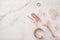 Skincare beauty concept. Top view photo of pink hairpins rose quartz roller gua sha gold rings and wristlet on white marble