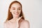 Skincare. Close-up of redhead woman with pale soft skin, smiling white teeth and touching clean no makeup face, looking