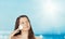 Skincare and sun protection in summer. Portrait of a beautiful young suntanned woman, blue sea and sky on background